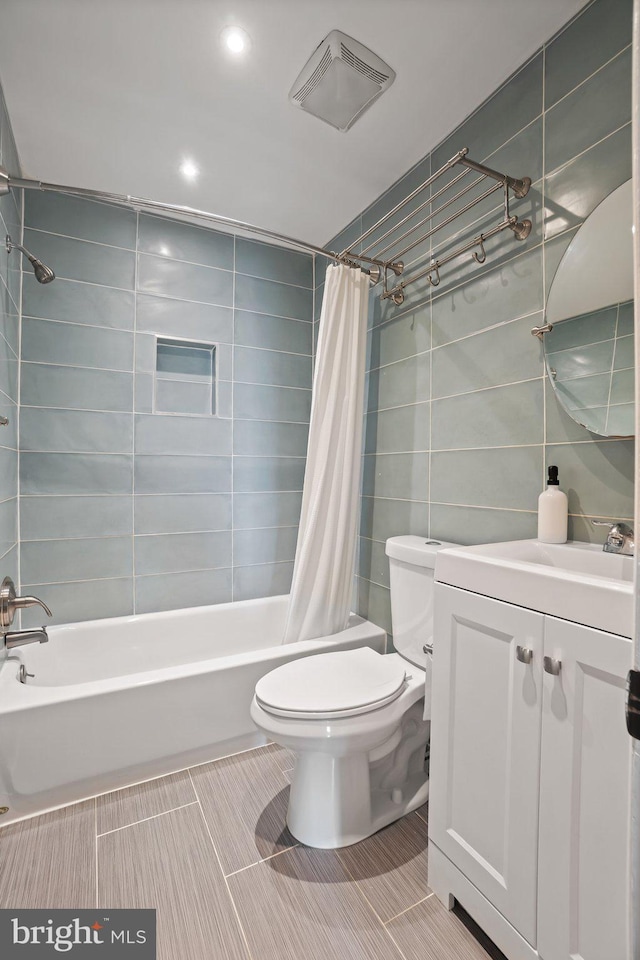 full bathroom featuring shower / bath combo, vanity, toilet, and tile walls