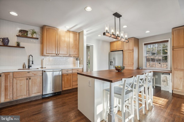 kitchen featuring decorative backsplash, stainless steel appliances, sink, pendant lighting, and a kitchen island