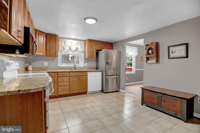 kitchen featuring stainless steel appliances, light stone countertops, and sink