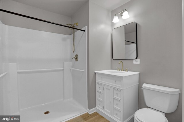 bathroom featuring hardwood / wood-style flooring, vanity, toilet, and a shower