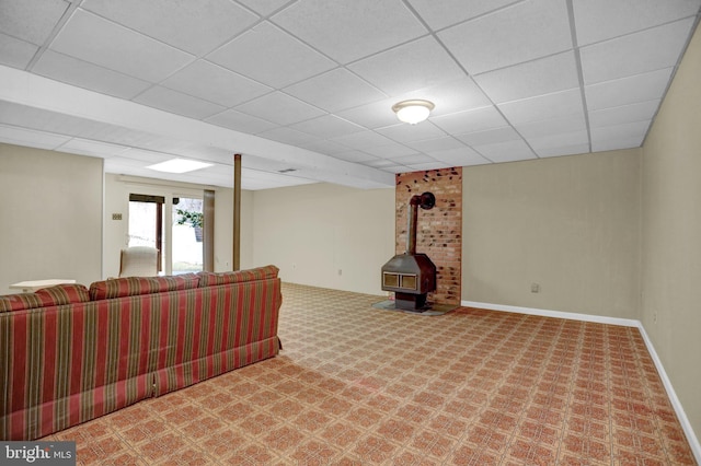 basement featuring carpet floors, a drop ceiling, and a wood stove