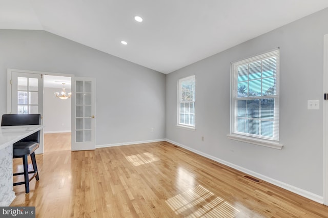 interior space featuring french doors, wood-type flooring, lofted ceiling, and an inviting chandelier