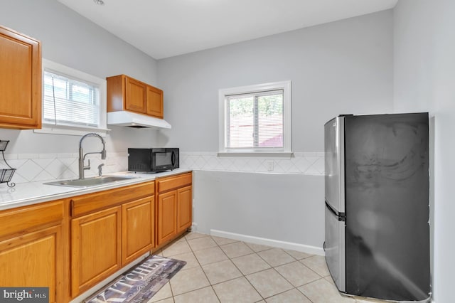 kitchen featuring stainless steel fridge, light tile patterned floors, and sink