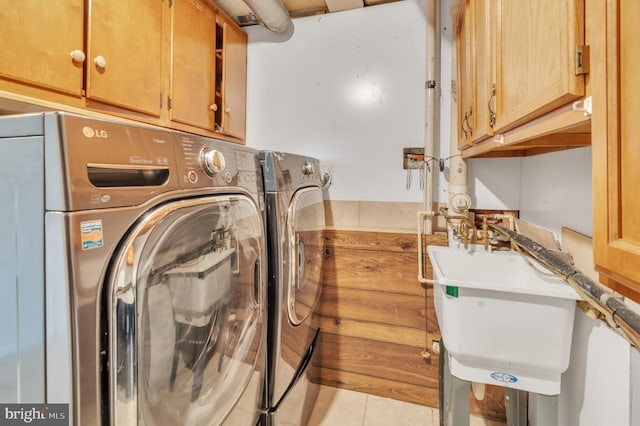 washroom with washing machine and clothes dryer, sink, light tile patterned flooring, and cabinets