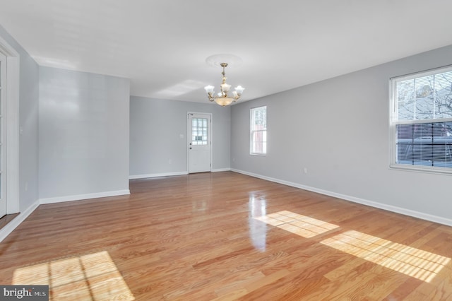 unfurnished room with light hardwood / wood-style flooring and an inviting chandelier