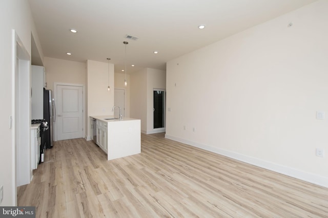 kitchen with white cabinetry, sink, pendant lighting, light hardwood / wood-style floors, and appliances with stainless steel finishes