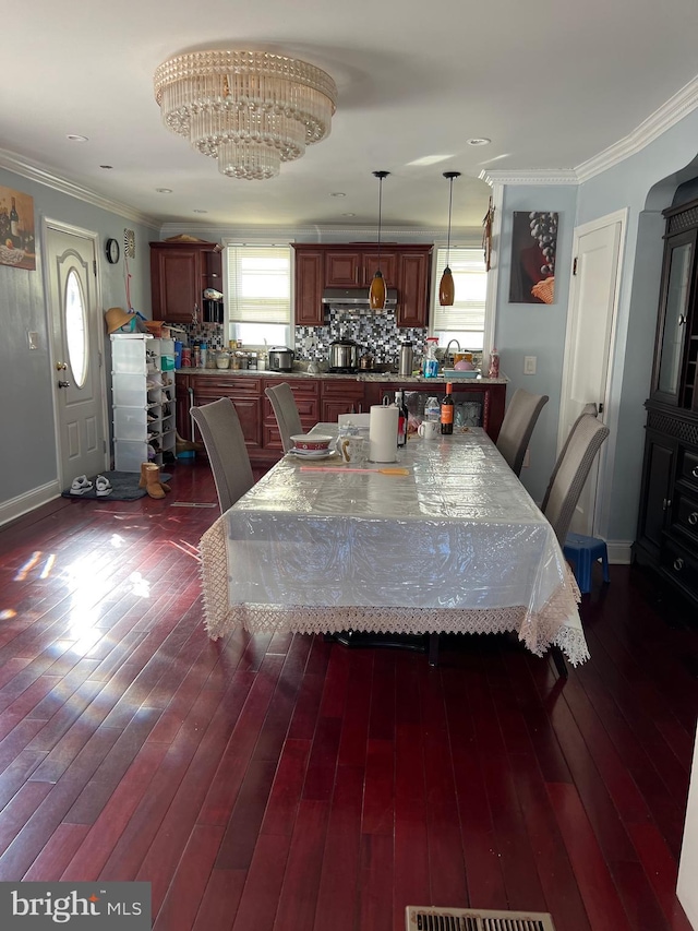 dining room featuring a chandelier, ornamental molding, and dark wood-type flooring