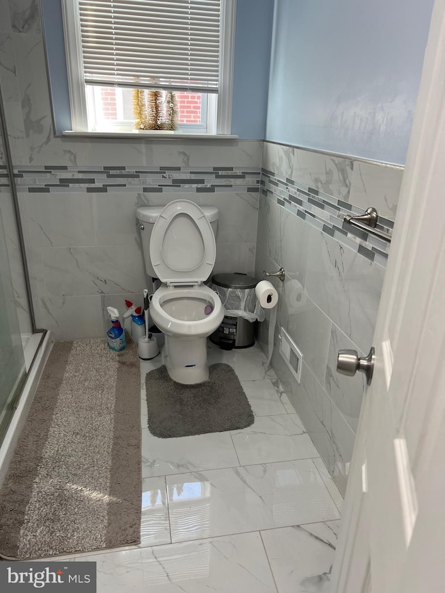 bathroom featuring a shower, toilet, and tile walls