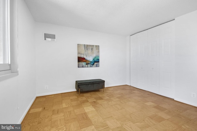 unfurnished living room featuring light parquet floors and a textured ceiling