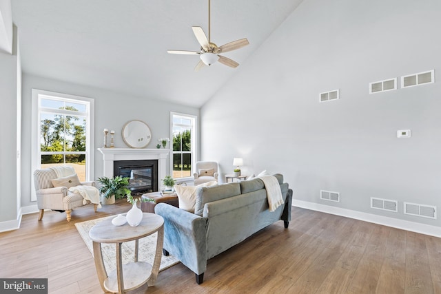 living room featuring ceiling fan, high vaulted ceiling, and light wood-type flooring