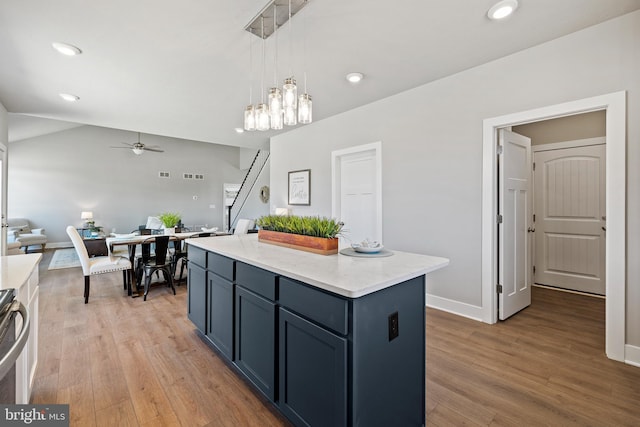 kitchen with a center island, vaulted ceiling, light wood-type flooring, pendant lighting, and ceiling fan