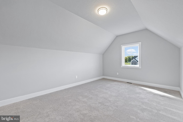 bonus room with vaulted ceiling, a textured ceiling, and carpet