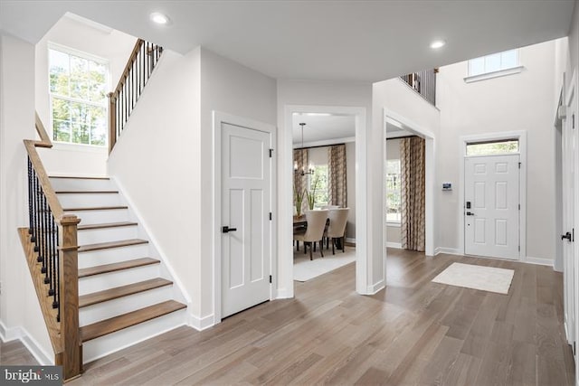 foyer entrance featuring hardwood / wood-style floors, plenty of natural light, and an inviting chandelier