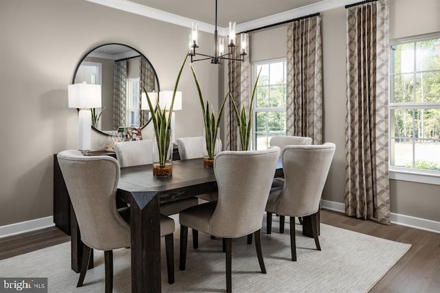 dining area with a notable chandelier, ornamental molding, and dark wood-type flooring