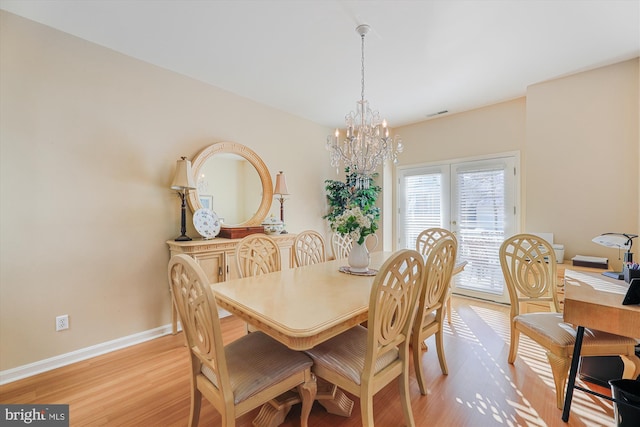 dining room with light wood-type flooring and a chandelier