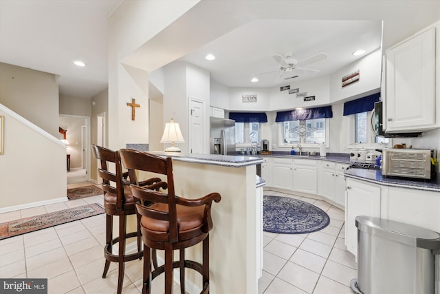 kitchen with sink, stainless steel appliances, white cabinetry, and light tile patterned floors