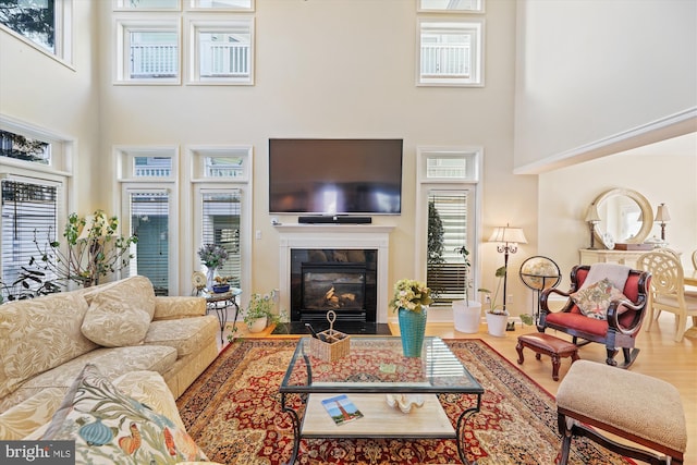 living room featuring a towering ceiling, a tile fireplace, and hardwood / wood-style floors