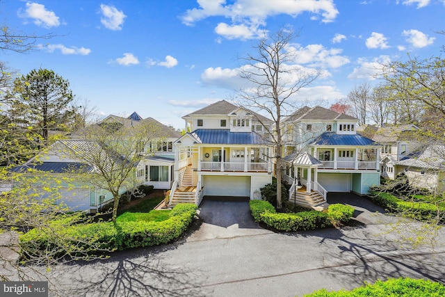 39281 Piney Dr Unit 55115, Bethany Beach, DE 19930 - view of front facade featuring a standing seam roof, driveway, metal roof, a garage, and stairs