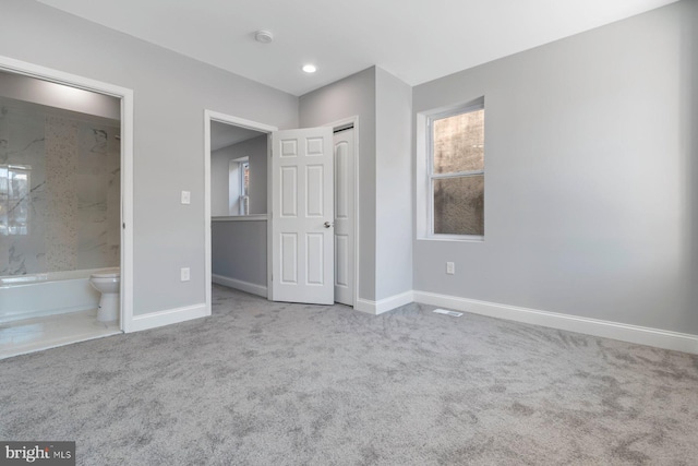 unfurnished bedroom featuring connected bathroom and light colored carpet