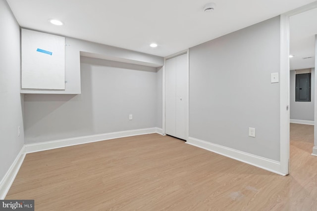 basement featuring light hardwood / wood-style floors and electric panel