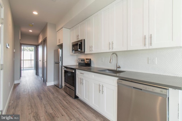 kitchen featuring sink, decorative backsplash, light wood-type flooring, appliances with stainless steel finishes, and white cabinetry