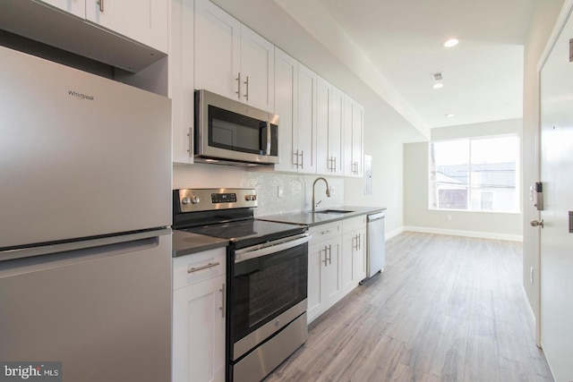 kitchen with sink, white cabinets, light wood-type flooring, and appliances with stainless steel finishes