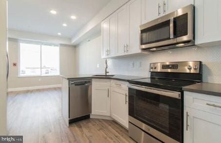 kitchen featuring light hardwood / wood-style floors, white cabinetry, sink, and appliances with stainless steel finishes