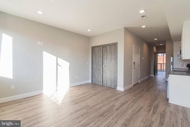 interior space featuring white cabinets, light wood-type flooring, and sink