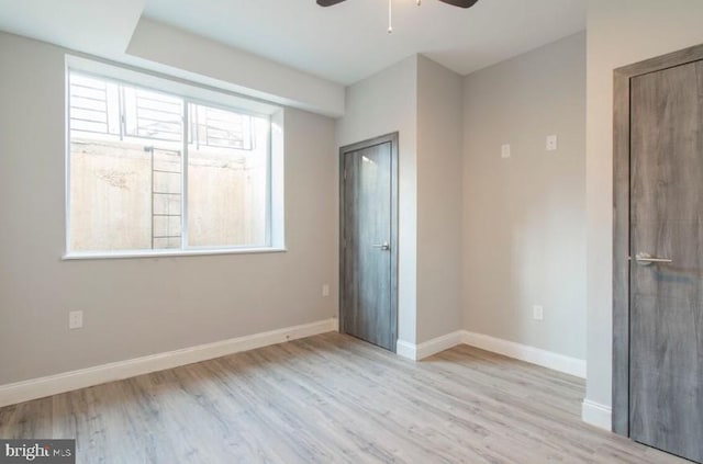 unfurnished bedroom with multiple windows, ceiling fan, and light wood-type flooring