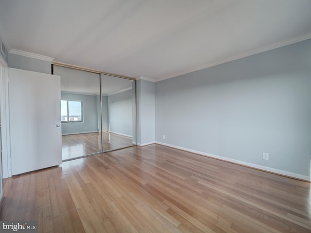 unfurnished bedroom featuring crown molding, a closet, baseboards, and light wood-style floors