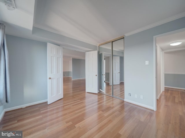 unfurnished bedroom featuring ornamental molding, light wood-type flooring, and baseboards