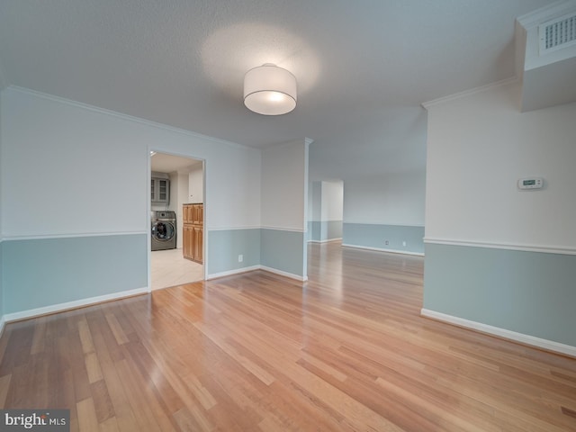 unfurnished room with light wood finished floors, washer / clothes dryer, ornamental molding, and visible vents