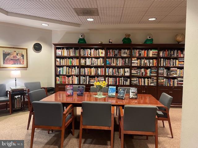 interior space featuring recessed lighting, light colored carpet, and wall of books