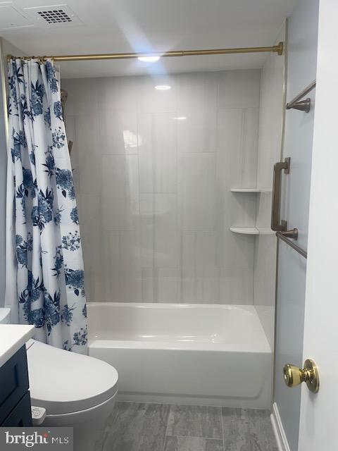 bathroom with visible vents, shower / tub combo, toilet, and vanity