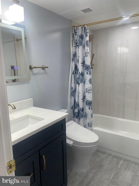 full bathroom with visible vents, shower / tub combo, vanity, and toilet