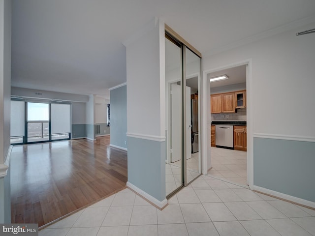 empty room featuring ornamental molding, visible vents, baseboards, and light tile patterned floors