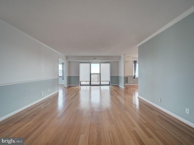 unfurnished living room with light wood-style floors, baseboards, and crown molding