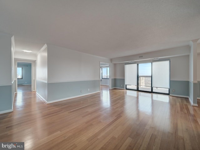 unfurnished room with light wood-type flooring, baseboards, and ornamental molding