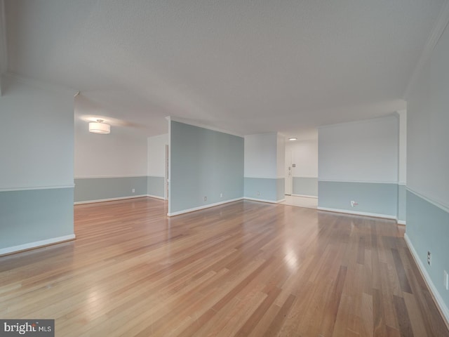 spare room featuring light wood-style flooring, baseboards, and ornamental molding