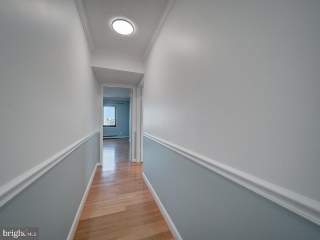 hallway featuring ornamental molding, baseboards, a textured ceiling, and light wood finished floors