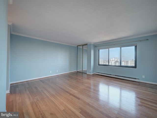 spare room featuring crown molding, light wood-style flooring, and baseboard heating