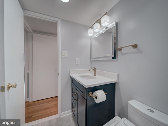 bathroom featuring baseboards, vanity, and toilet