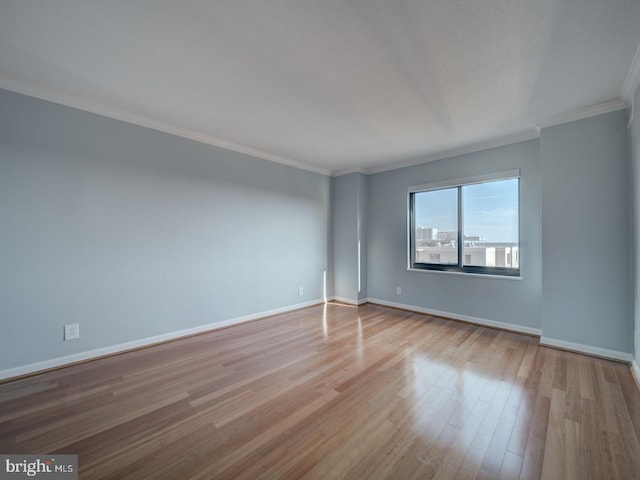 empty room featuring baseboards, crown molding, and light wood-style floors