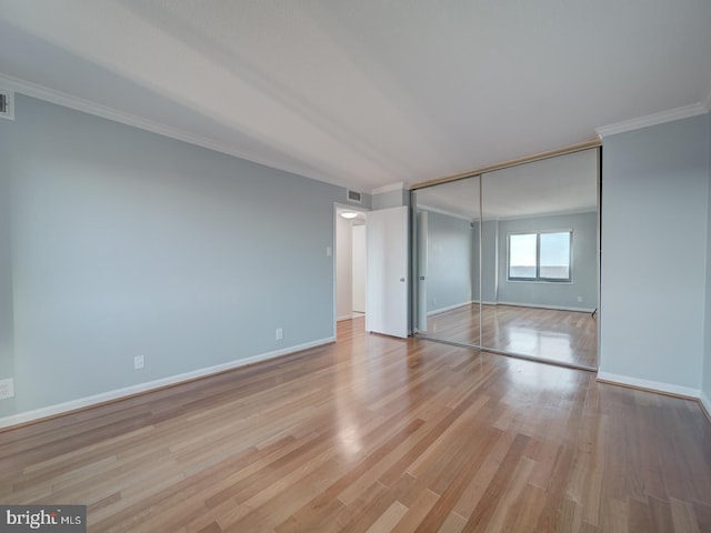 unfurnished bedroom featuring light wood-style floors, a closet, baseboards, and crown molding