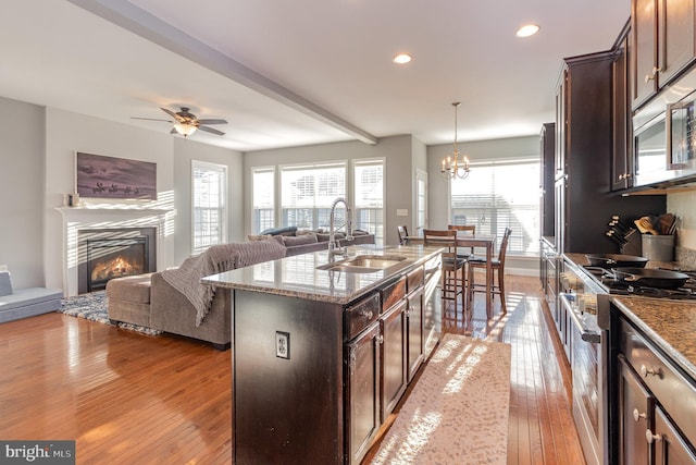 kitchen featuring pendant lighting, a center island with sink, sink, dark brown cabinets, and stainless steel appliances