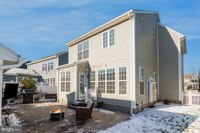 snow covered house featuring a patio area and an outdoor fire pit