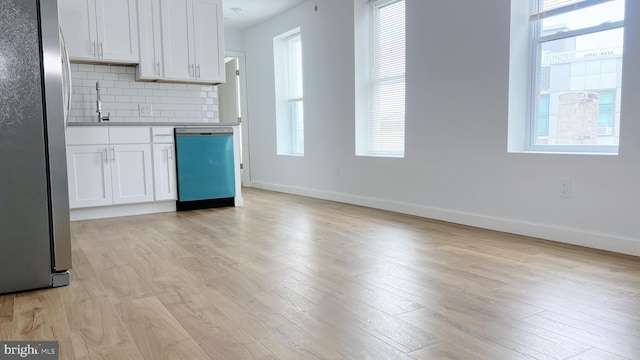 kitchen featuring white cabinets, sink, light hardwood / wood-style flooring, decorative backsplash, and appliances with stainless steel finishes