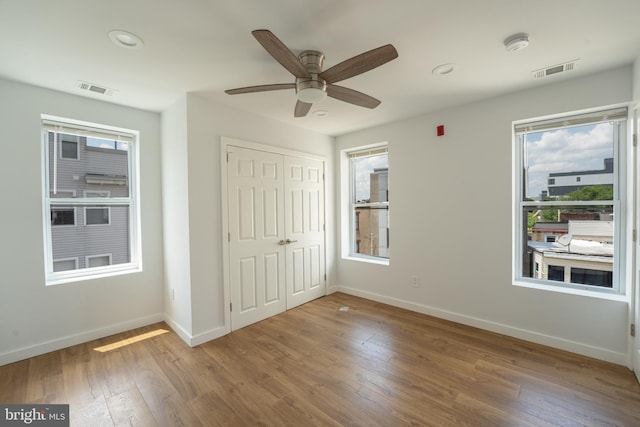 unfurnished bedroom with hardwood / wood-style flooring, a closet, and ceiling fan