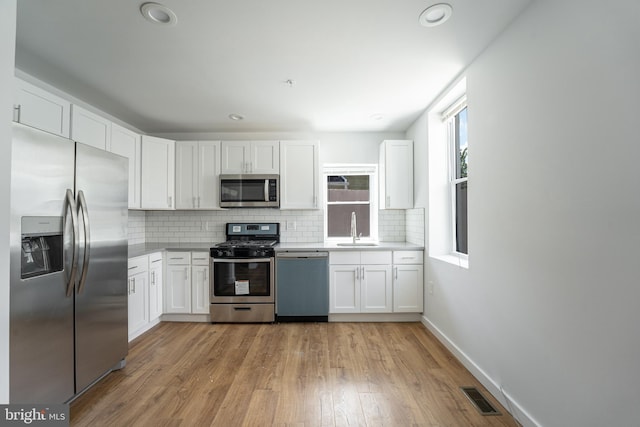 kitchen featuring decorative backsplash, stainless steel appliances, white cabinetry, and sink