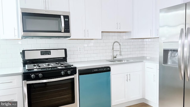 kitchen featuring decorative backsplash, stainless steel appliances, white cabinetry, and sink